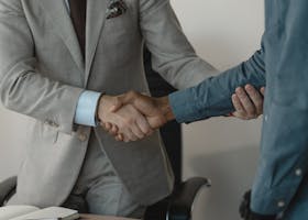 Image of a professional handshake between two businessmen in an office setting.